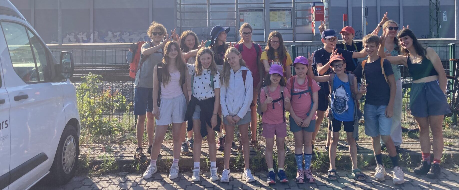 Quatsch beim Warten auf den Zug: Die DAV-Sommerfreizeit-Kinder mit ihren Betreuer*innen. Foto: C. Häussler